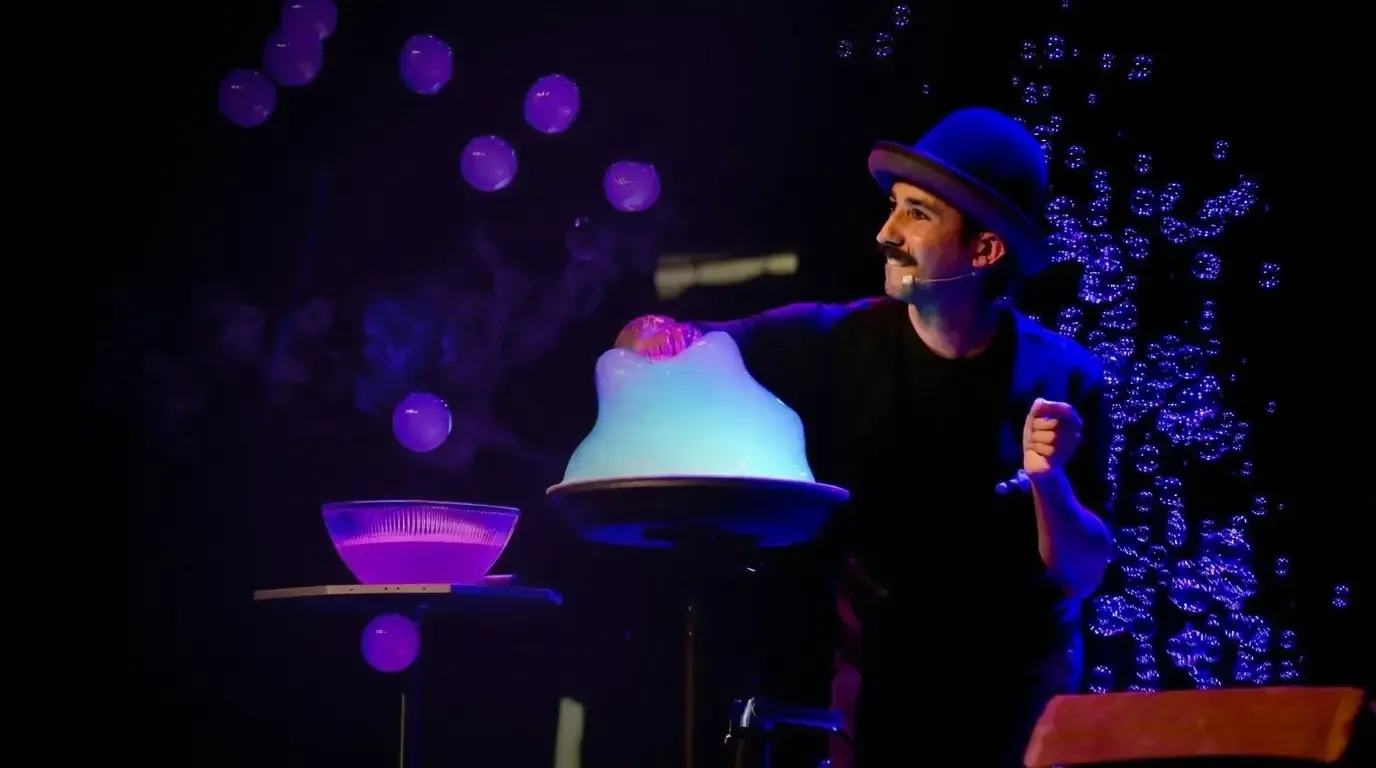 Show central — escenario y público envueltos en penumbra cálida